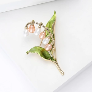 Élégante broche muguet avec perles et émail vert sur une base en métal doré