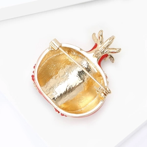 Macro view of the golden metal back and safety pin clasp of the pomegranate brooch