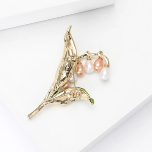 Élégante broche muguet dorée avec perles gouttes roses et blanches sur support blanc