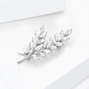 Détail d'une broche feuille avec cristaux marquise, métal argenté et perle blanche élégante