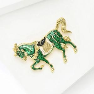 Dettaglio della spilla a cavallo con smalto verde e profilo in metallo dorato