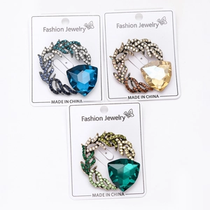 Close-up of elegant feather brooch pins with crystals in blue, gold and emerald colors