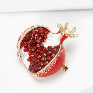 Artistic red enamel pomegranate brooch with gold beads on minimalist white background