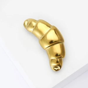 Macro detail of a croissant shaped gold stainless steel brooch with a polished finish