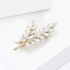 Broche épi de blé dorée élégante avec cristaux et perle blanche sur un socle épuré