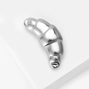 Detailed macro view of the polished silver croissant-shaped brooch with 3D metal texture