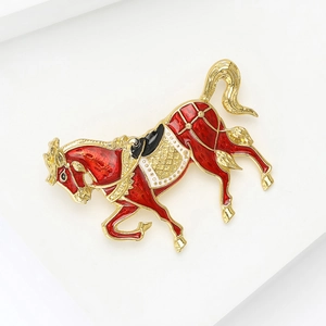 Dettaglio ravvicinato di una spilla a forma di cavallo dorata con smalto rosso