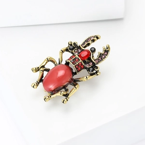 Detailaufnahme einer Vintage-Goldkäfer-Brosche mit rotem Ovalstein und Strasssteinen