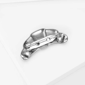 Detailed back view of silver croissant brooch with secure metal pin on white steps
