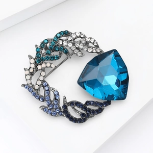 Detailed macro view of a circular brooch with a blue triangular gem and gradient rhinestones