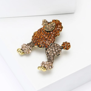 Détail de la broche caniche avec strass ambre et champagne sur un socle en métal doré poli