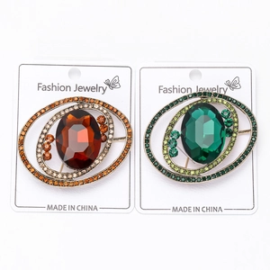 Close-up of vintage oval brooches with amber and emerald crystals in gold plating