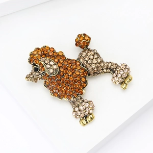 Vue détaillée de la broche caniche dorée avec strass ambrés sur un support blanc