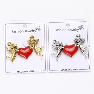 Detail view of gold and silver angel brooches with vibrant red enamel heart charms