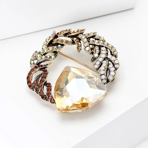 Macro view of vintage gold wreath brooch with champagne gemstone and colorful crystals