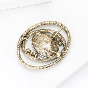 Back view of vintage gold-tone planet brooch with hammered metal texture and pin closure