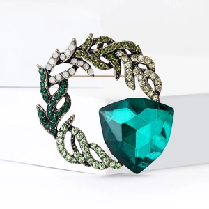 Detailed macro view of retro forest style brooch with large emerald green crystal and rhinestones
