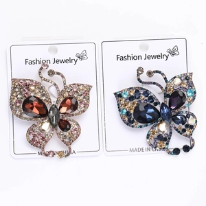 Detailed close-up of luxury rhinestone butterfly brooches in red and blue violet tones