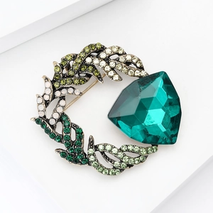 Macro detail of high-end brooch with emerald faceted crystal and multicolor rhinestones