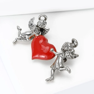 Close-up of vintage silver angel brooch with a red enamel heart on a white podium