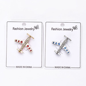 Détail de broches avion or et argent avec strass en cristal sur carte de présentation