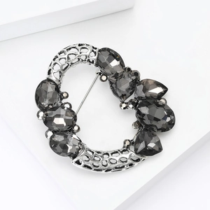 Detail of vintage round hollow brooch with dark grey crystals and silver metal texture