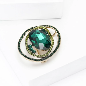 Detailed view of the planet brooch with green crystal and gold metal base