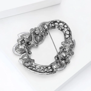 Macro shot of retro silver wreath brooch back showing pin structure and hammered texture
