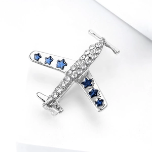 Détail d'une broche avion argentée avec des strass blancs et des gemmes bleues en étoile