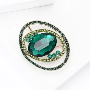 Detailed view of an oval vintage brooch with a dark green gemstone and small crystals