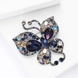 Luxurious hollow butterfly brooch with purple and blue crystals on white podium