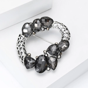 Detail of vintage luxury silver wreath brooch with gray faceted crystals on white pedestal