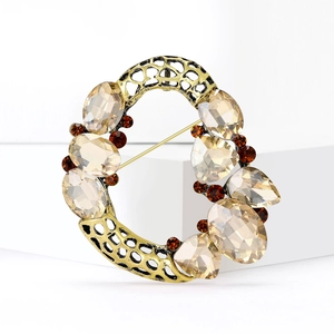 Vintage gold hollow wreath brooch with champagne crystals on a white display stand