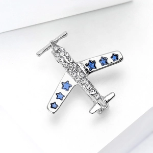 Détails de la broche avion argentée avec étoiles bleues et strass brillants sur fond blanc