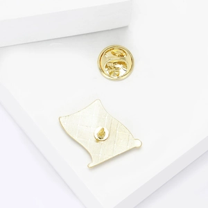 Golden Colombia flag pin with back butterfly clasp on minimalist white geometric stand