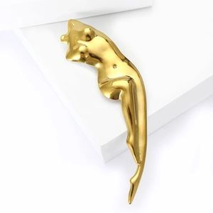 Macro view of polished gold abstract female torso sculpture brooch on a white base