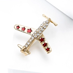 Détail de la broche avion dorée ornée de strass blancs et de petites étoiles rouges