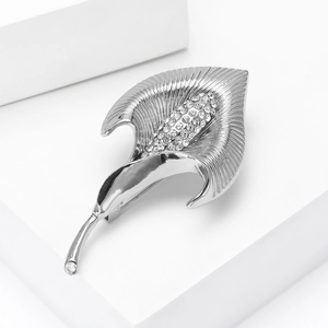 Vue macro d'une broche calla argentée sertie de strass sur un support géométrique
