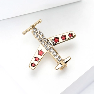 Détail de la broche avion dorée avec strass scintillants et étoiles rouges peintes