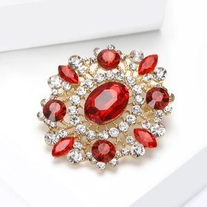 Macro detail of vintage gold brooch featuring large oval red crystal and rhinestone accents