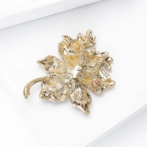 Back view of gold floral brooch with metallic petals and safety pin fastening