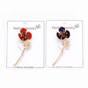 Detailed close-up of red and blue enamel poppy brooches with golden alloy plating