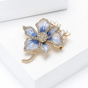 Close-up of blue and white gradient enamel flower brooch with rhinestones on a white stand