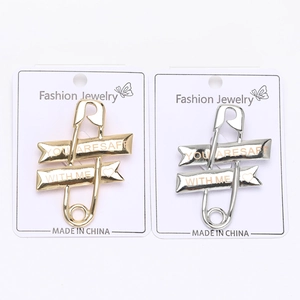 Detailed view of gold and silver safety pin brooches with You Are Safe With Me engraving