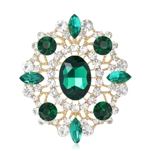 Elegant gold-tone oval brooch with vintage openwork design and emerald green rhinestones