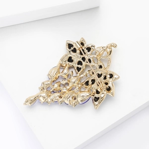 Close-up of the golden brooch back showing the pin closure and fine textured finish
