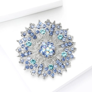 Detail of flower brooch with blue crystals and silver metal on white geometric base