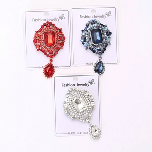 Detailed macro view of vintage crystal brooches with colorful glass pendants in a trio layout