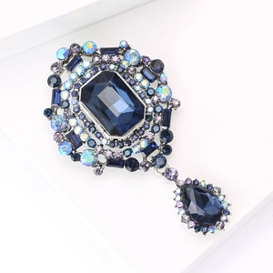 Macro shot of vintage brooch featuring a blue crystal center and a teardrop pendant