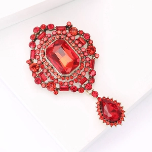 Macro detail of luxury vintage red crystal brooch with drop pendant on white background